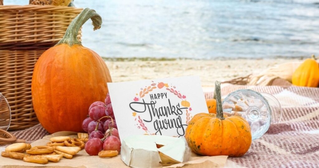 Pumpkin, cheese and card with text HAPPY THANKSGIVING on beach