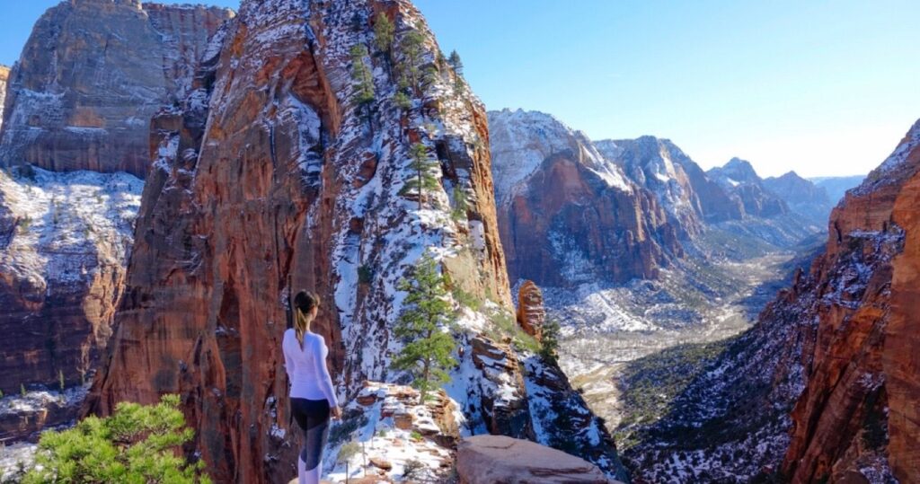 10 trilhas para caminhadas que oferecem vistas de inverno que valem a pena enfrentar o frio 9 Woman hiking Zion National Park in winter