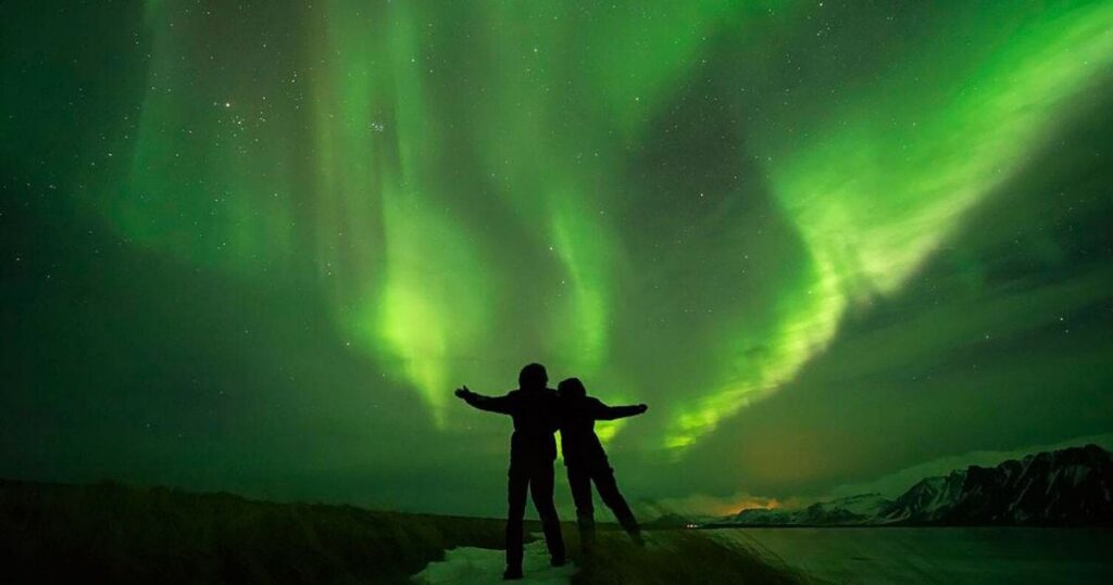 A couple outlined in shadow watching Aurora Borealis in Ireland
