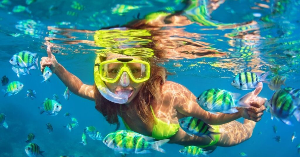 a woman snorkeling with fish