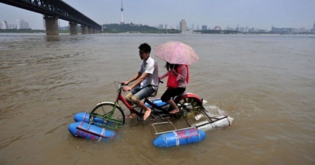 A couple on an invention from China, the water bicycle, with the cityscape in the background